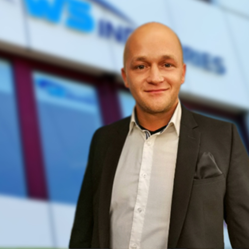 Mann in Anzug lächelt vor Firmenlogo