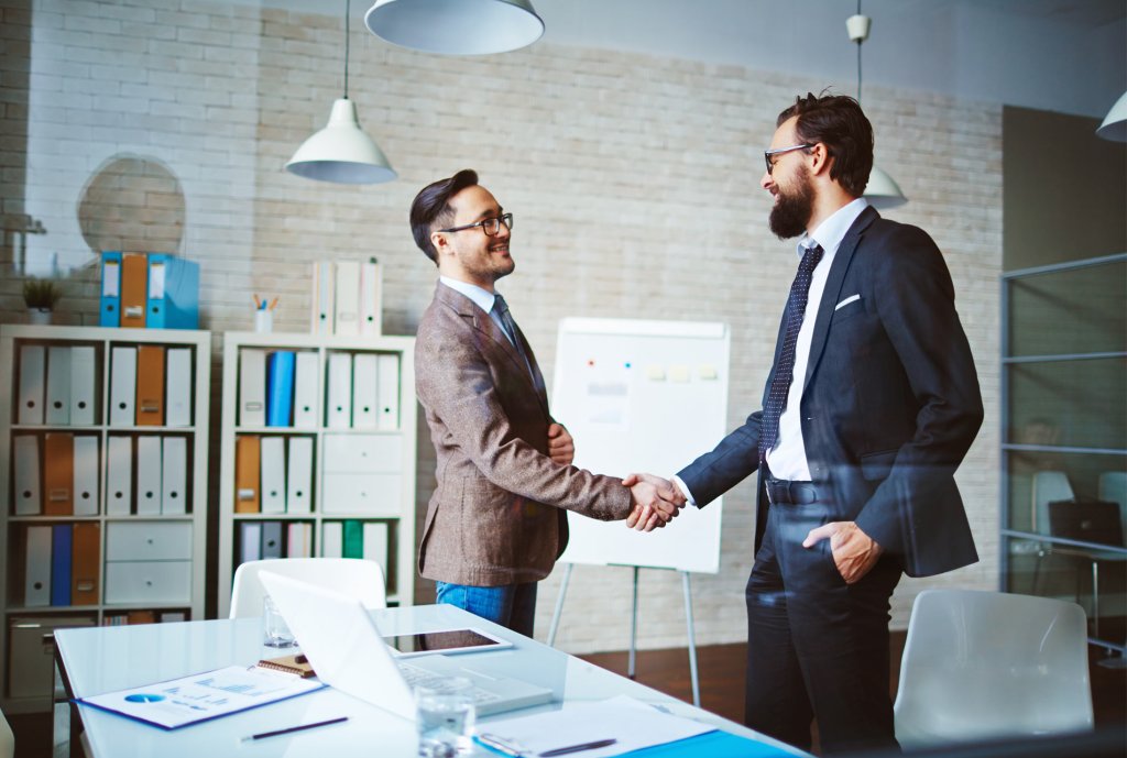 Zwei Geschäftsleute geben sich die Hand im Büro.