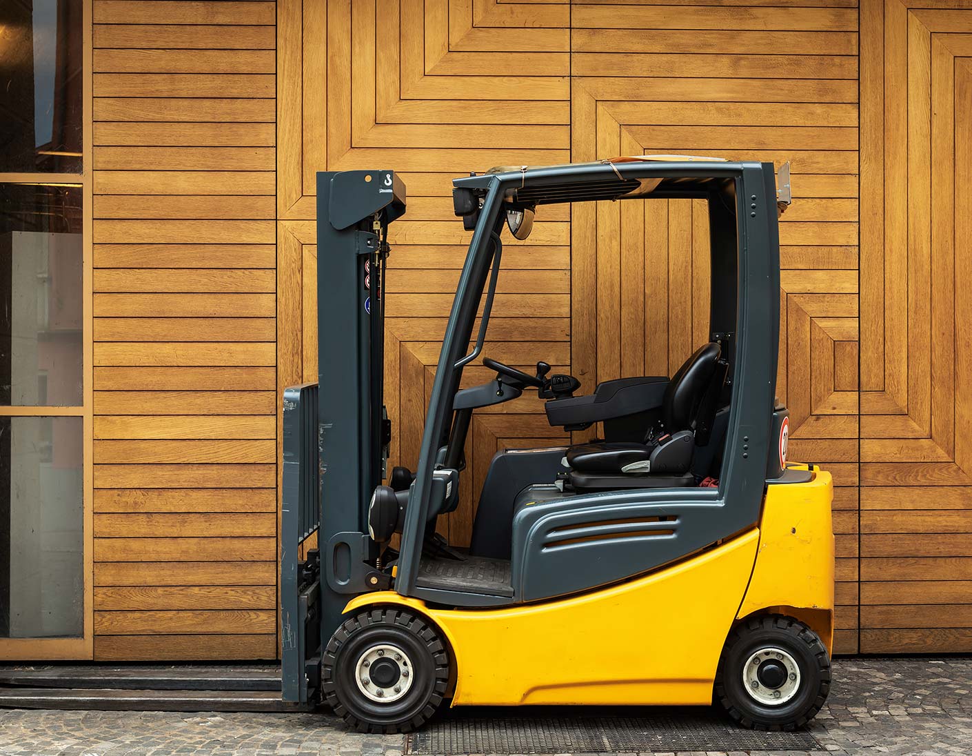 Gelber Gabelstapler vor Holzwand