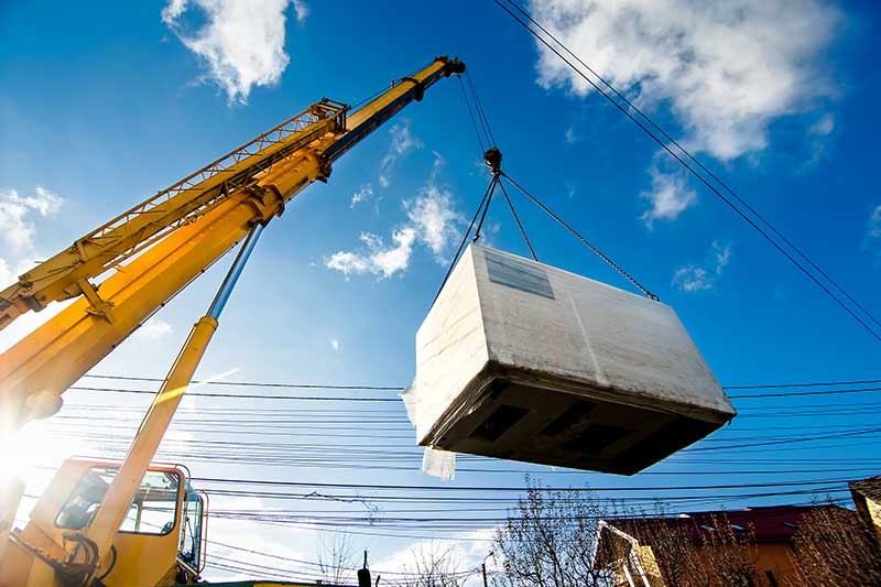 Kran hebt großen Betonblock an sonnigem Tag