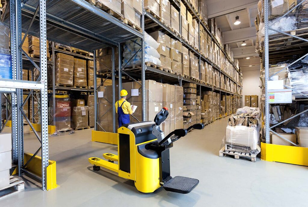 Arbeiter im Lager mit Gabelstapler und Regalen